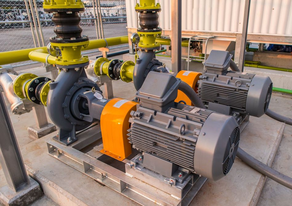 Industrial pumps and electric motors with yellow pipes in a factory setting