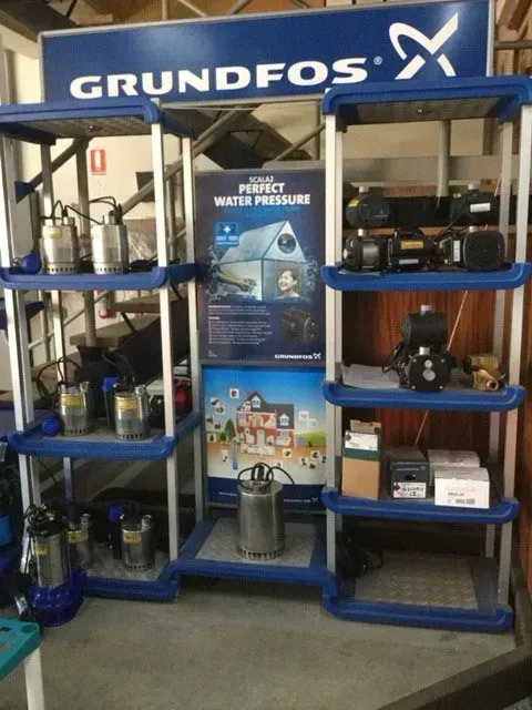 GRUNDFOS display booth with blue shelves, water pumps, and promotional posters at an expo