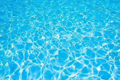Bright blue swimming pool water with sunlight reflections and ripples