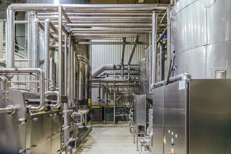 Industrial plant interior with stainless steel tanks, pipes, and machinery in a clean processing room