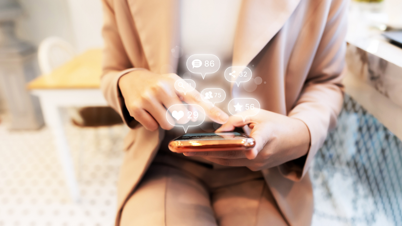 a woman is sitting at a table using a smart phone .