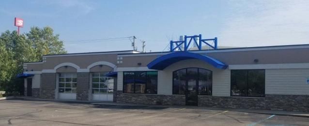 Exterior of a business with a blue awning, blue accents, and a red sign against a blue sky.