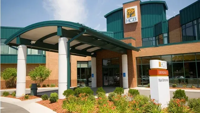 Hospital entrance with a teal awning, brick, and a sign that reads