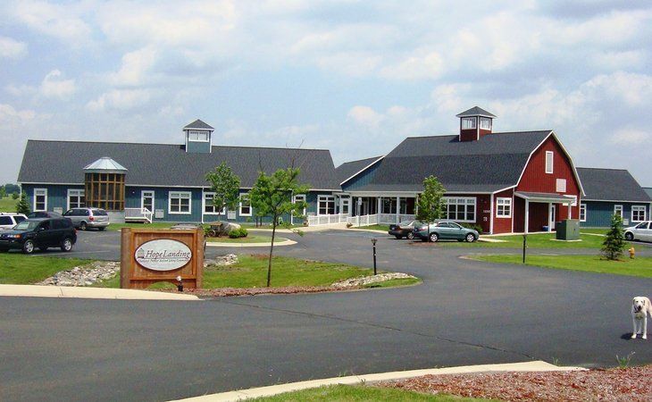 A campus-style building with a red barn and blue buildings, sunny day.