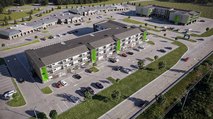 Aerial view of an apartment complex with green accents, a retail area, and a parking lot.