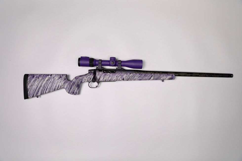 Purple scoped rifle with white and gray patterned stock on white background.