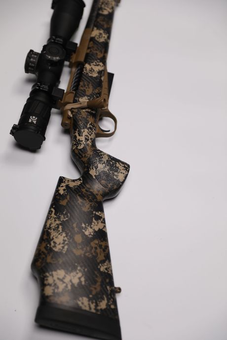 Camouflaged hunting rifle with scope, on a white background.