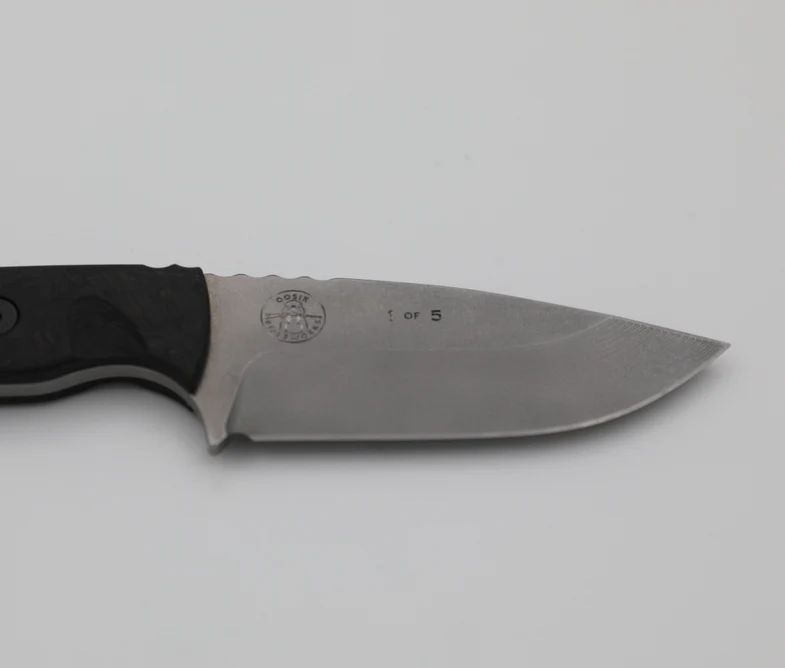 Close-up of a fixed-blade knife with a black handle and a silver blade, marked 