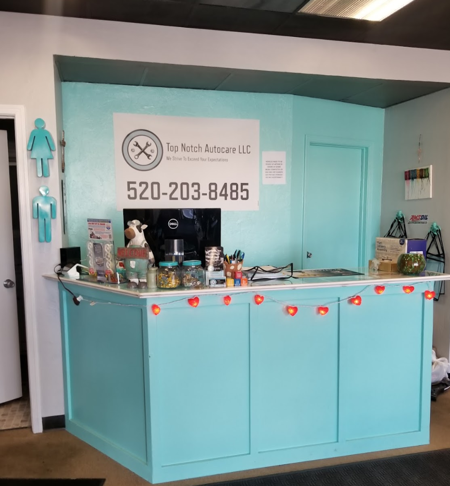 Turquoise reception desk at a business, with a phone number visible. Includes restrooms and decorations.  | Top Notch Autocare