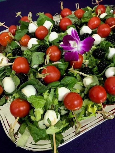 A salad with tomatoes blackberries and mozzarella on toothpicks