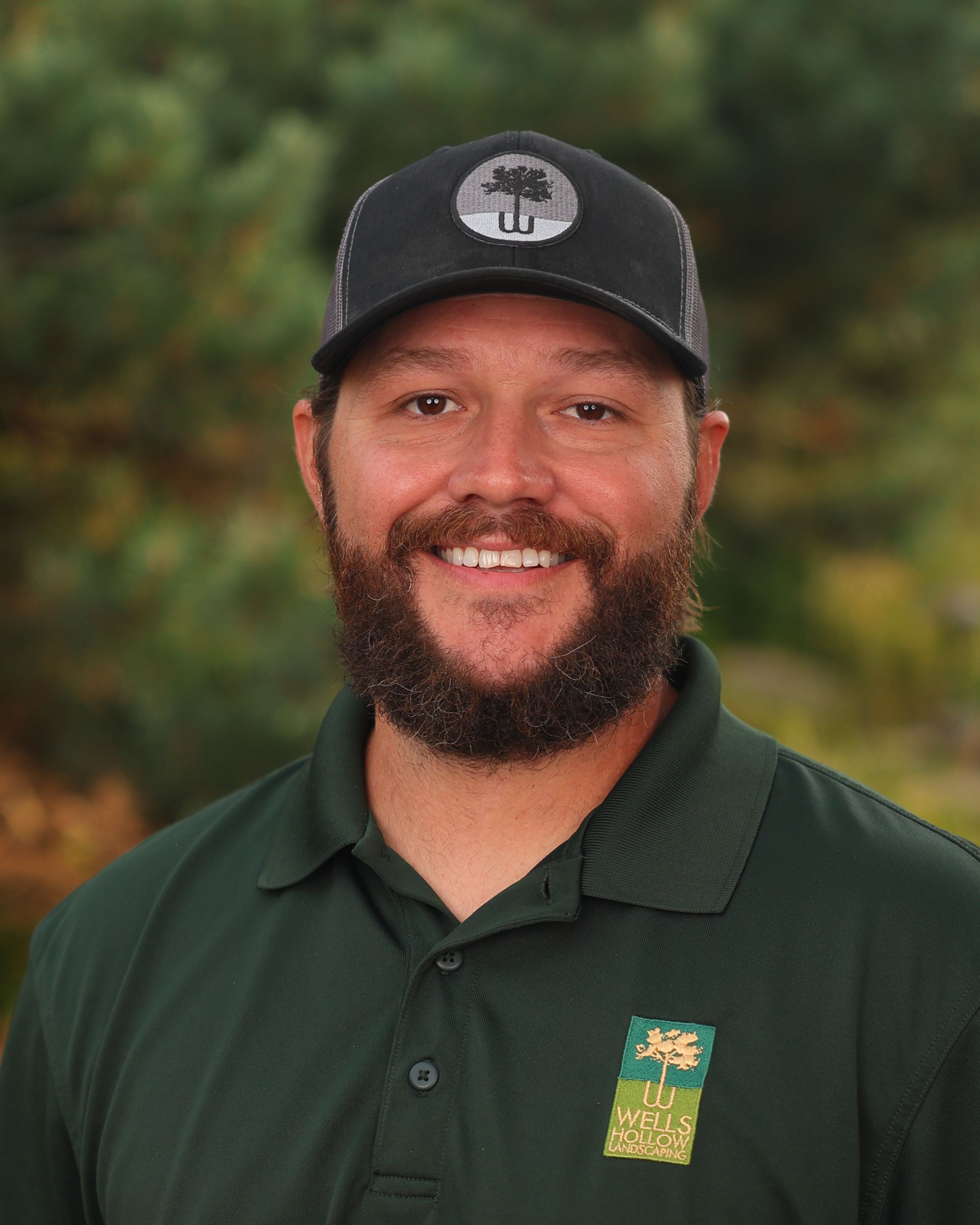 A man with a beard wearing a black hat and a green shirt