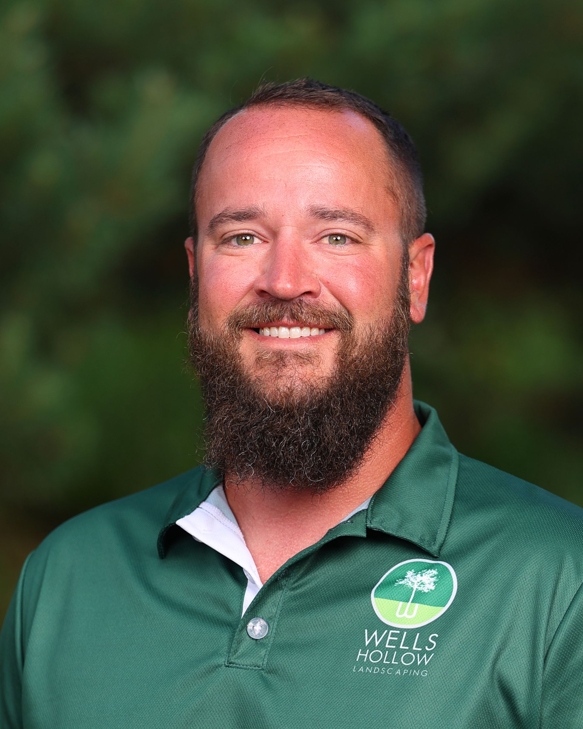 A man with a beard wearing a hat and a green shirt