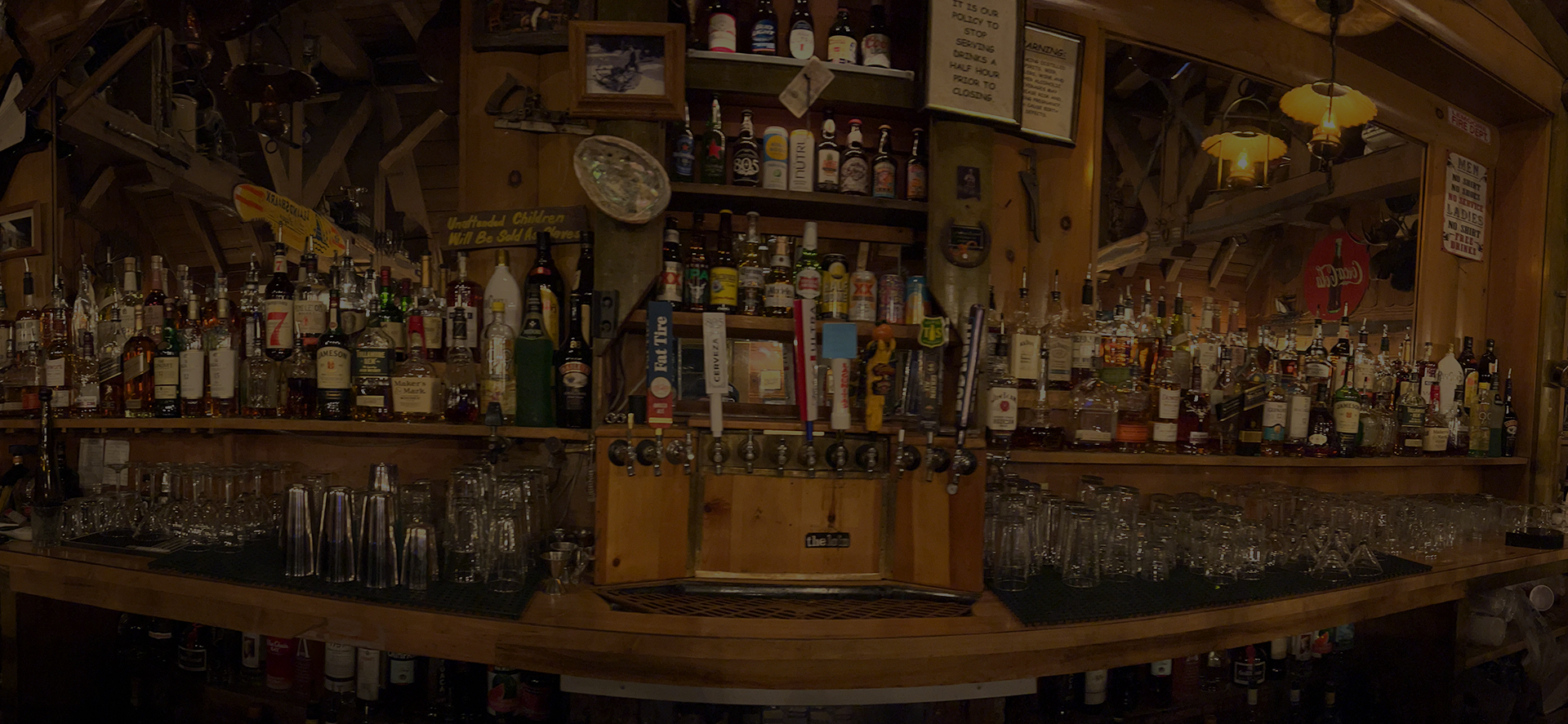 A well-stocked bar with various bottles and glasses, made of wood.