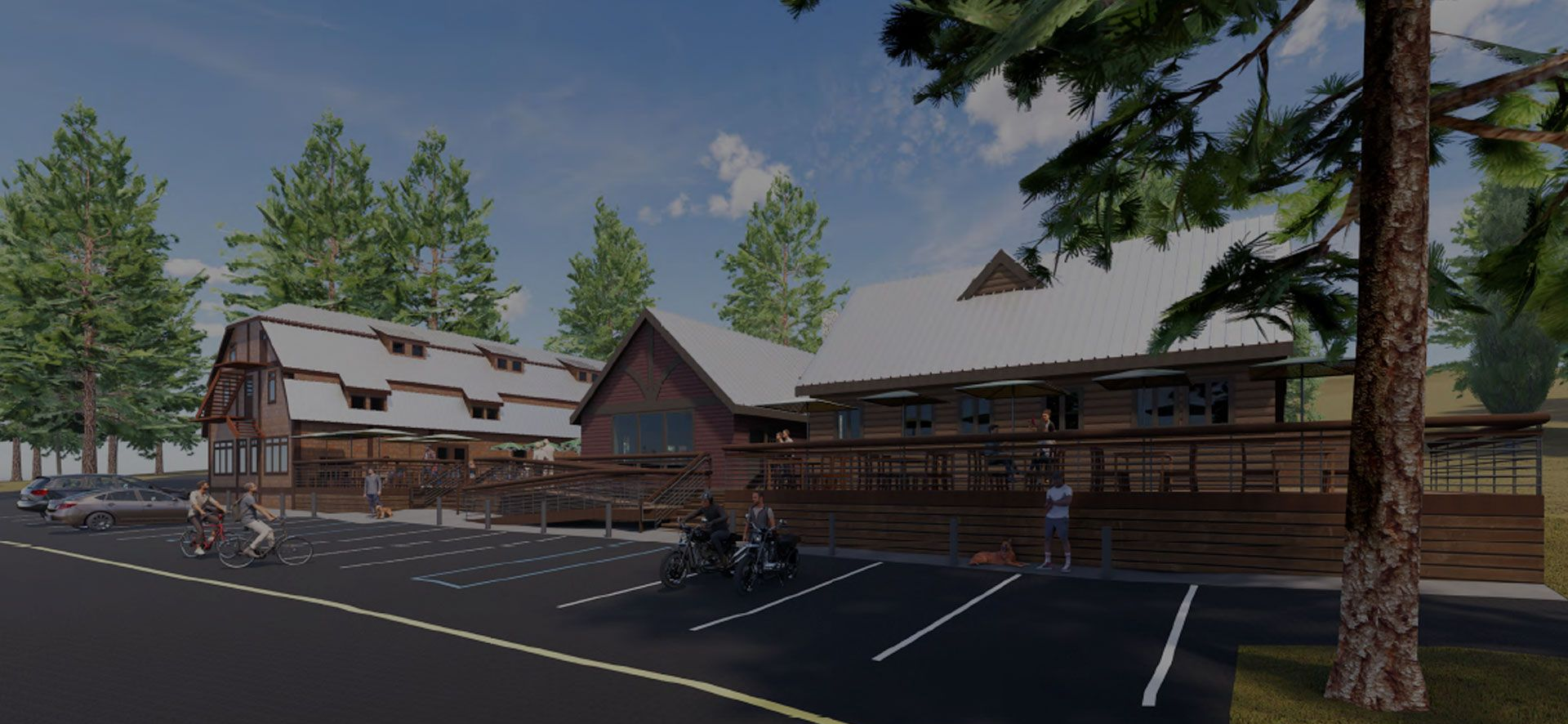 Wooden buildings with a deck and a parking lot. Trees surround the structure and a bright sky is visible.