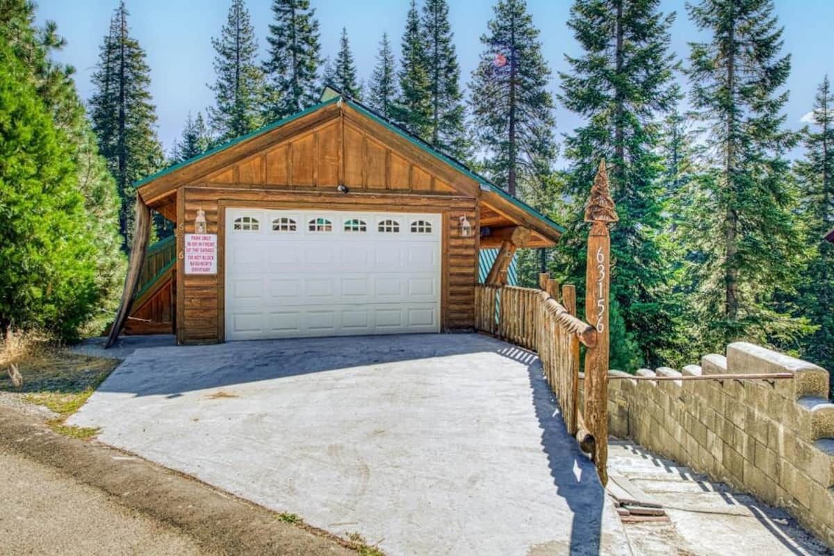 Wooden garage with white door and stone driveway on a wooded hillside