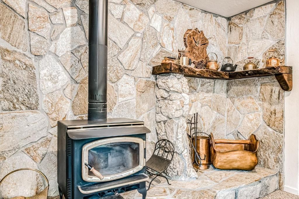 Stone fireplace corner with wood stove, log shelf, and basket on a rustic wall