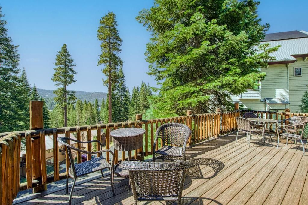 Wooden deck with patio chairs and tables overlooking trees and mountains on a sunny day