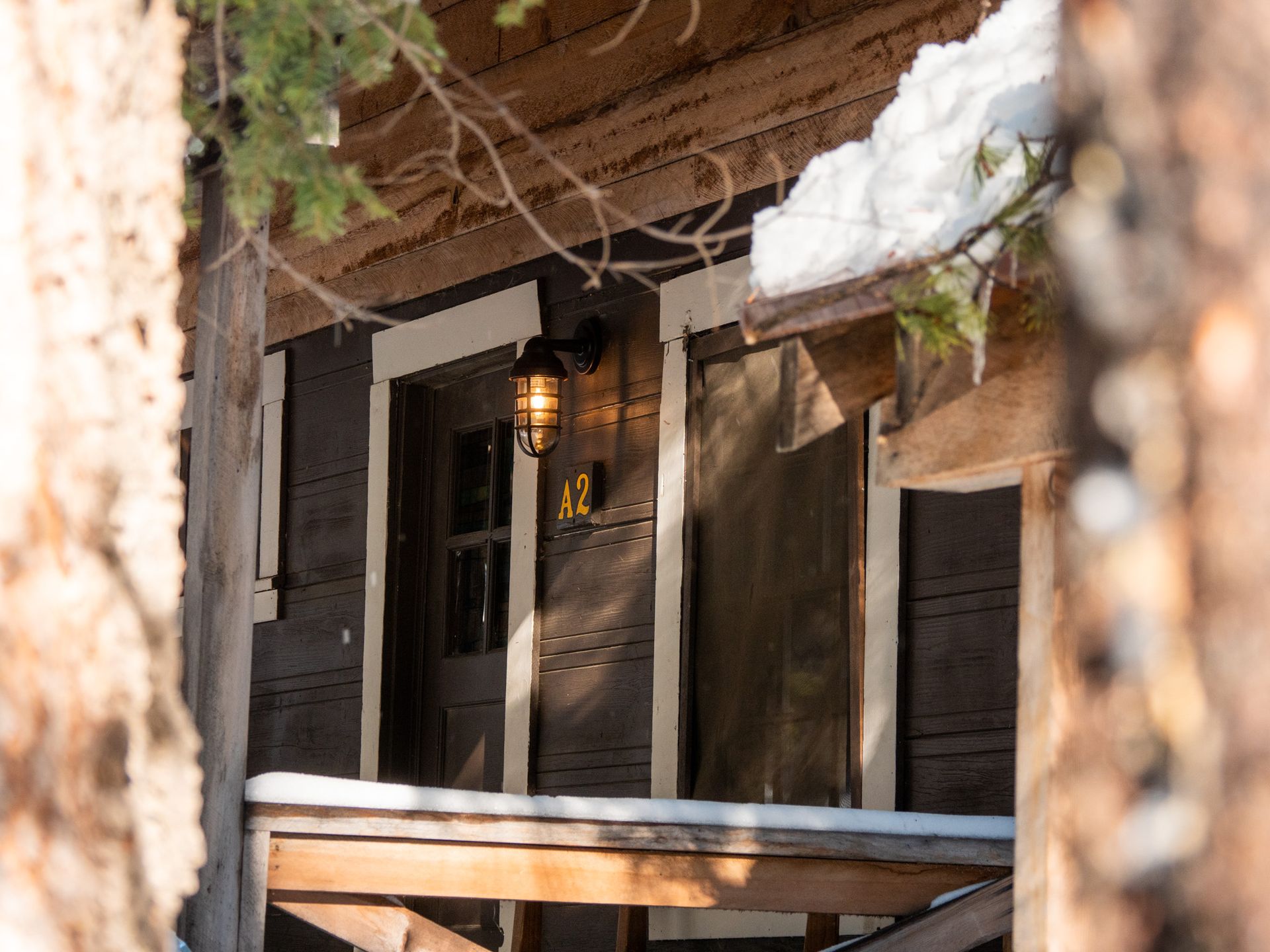 Rustic porch with a lantern, white shutters, and stone wall detail