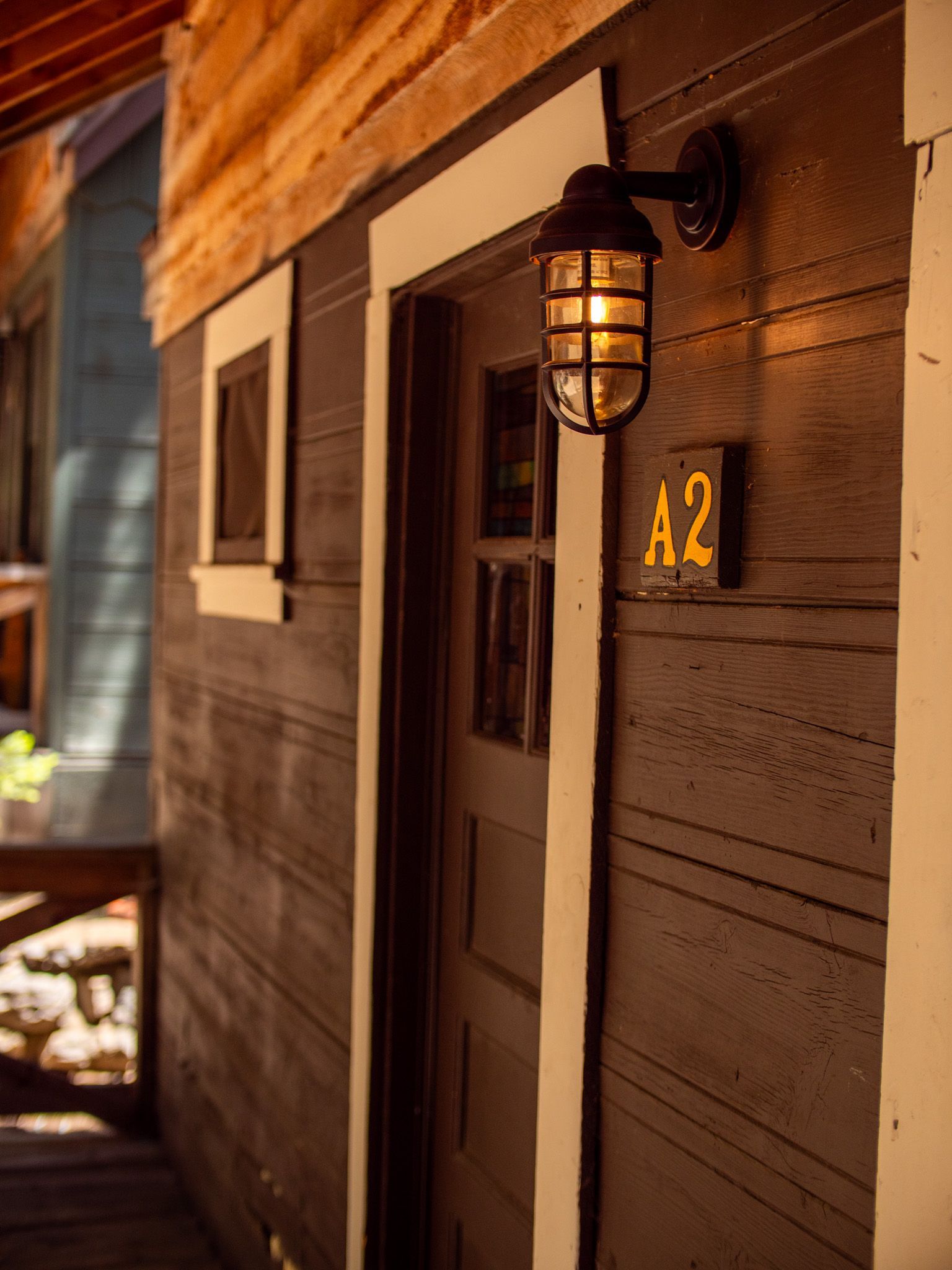 Rustic wooden cabin entrance with a lit lantern and an A2 sign beside the door