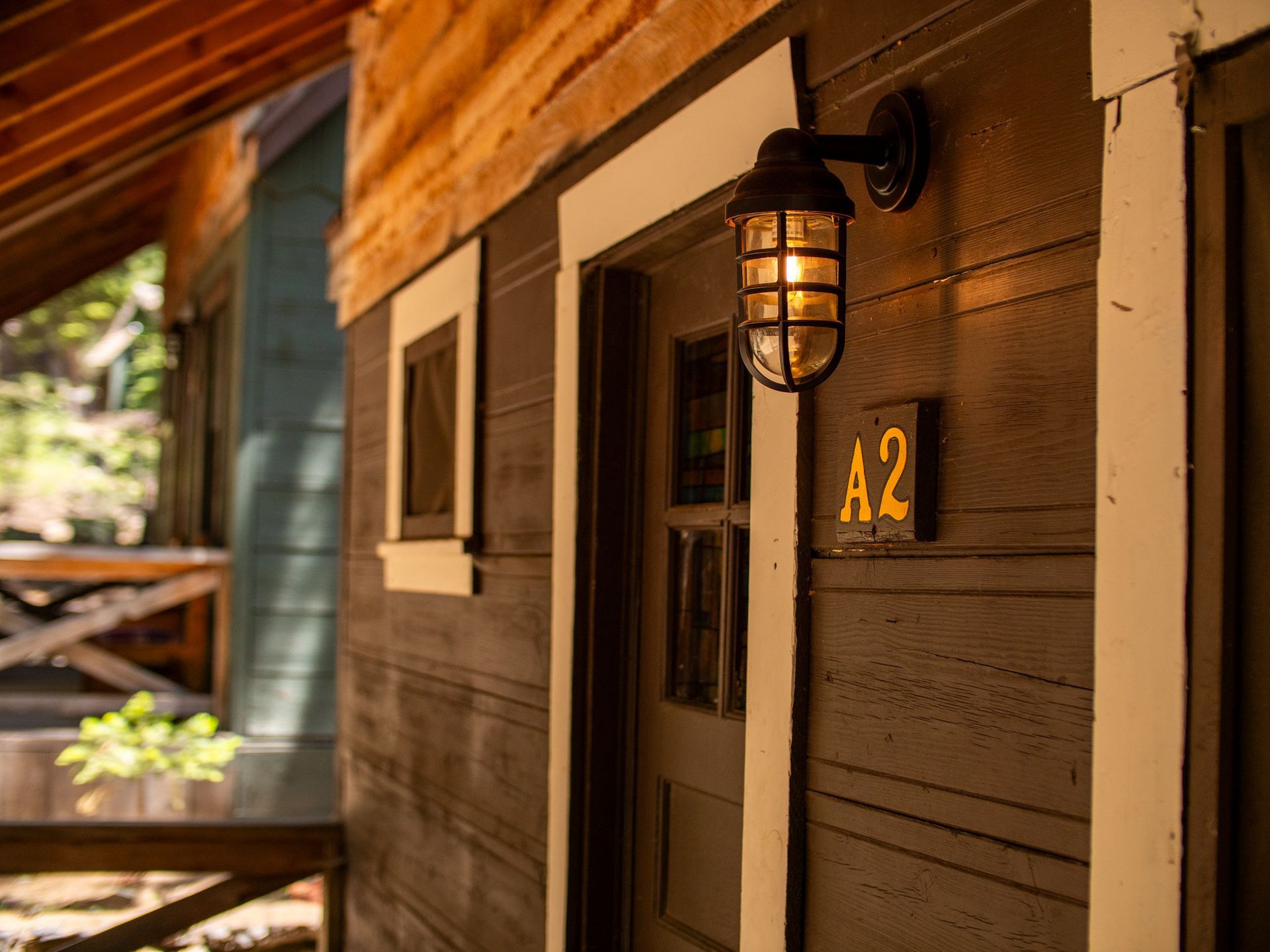 Wooden cabin porch with lit lantern and door marked A2