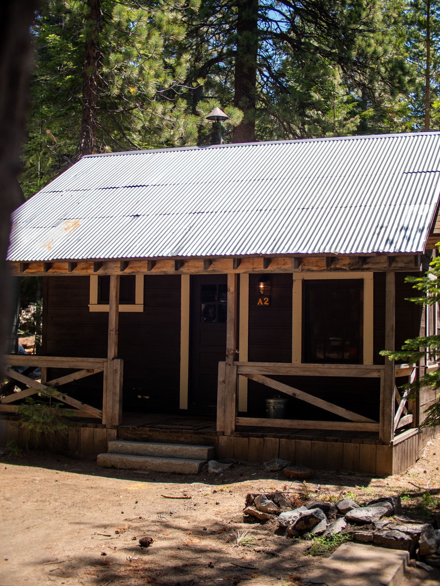 Small rustic cabin with a corrugated metal roof in a wooded clearing.