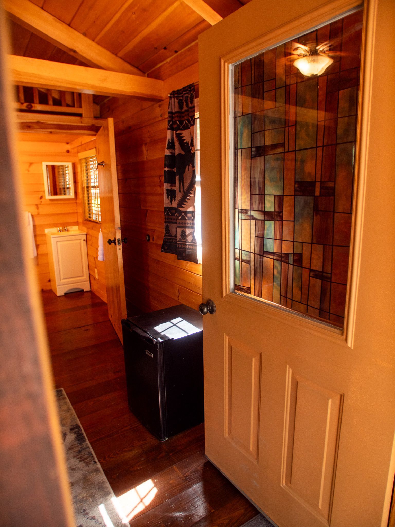 Sunlit wooden hallway with an open door and white cabinets in a cozy interior