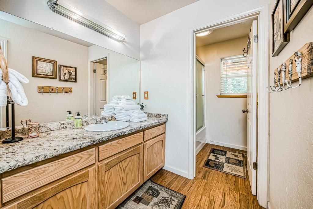 Bright bathroom with double vanity, granite countertop, large mirror, wood cabinets, and adjacent toilet area