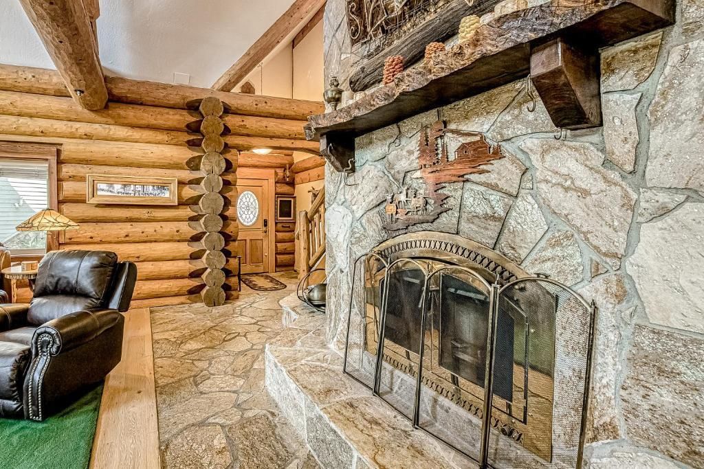 Rustic log cabin living room with stone fireplace and leather chairs