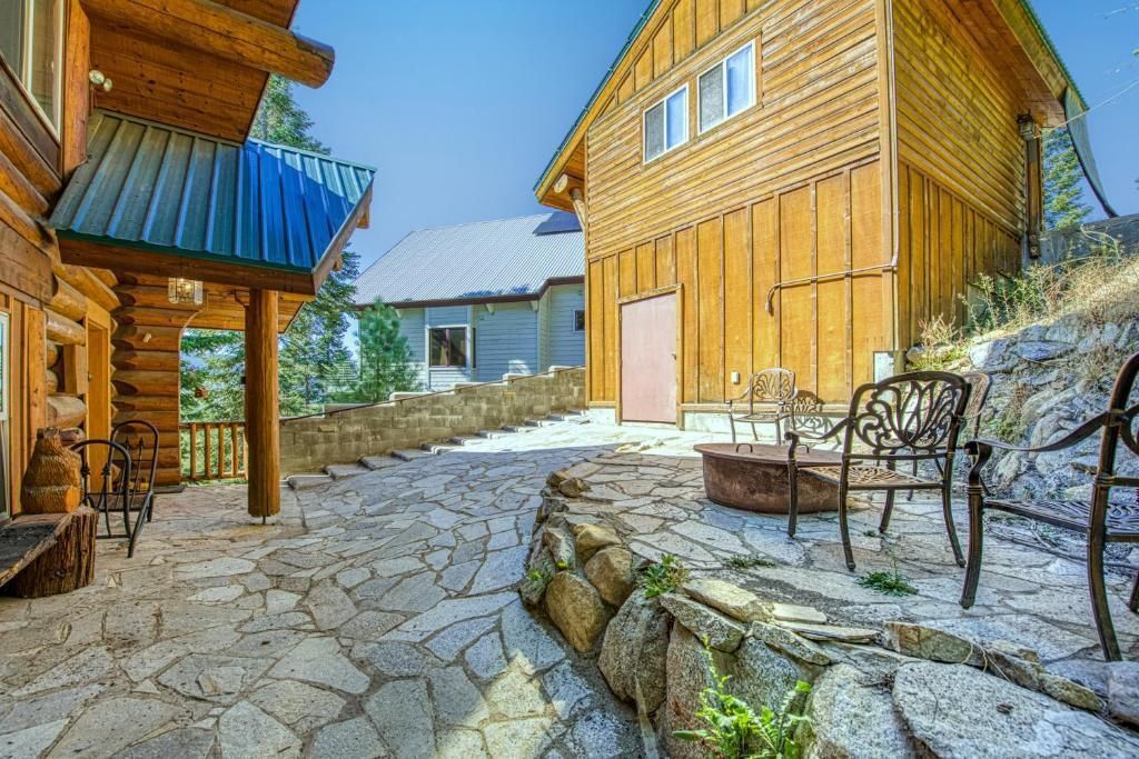 Sunny rustic cabin courtyard with stone path, wooden buildings, and outdoor chairs