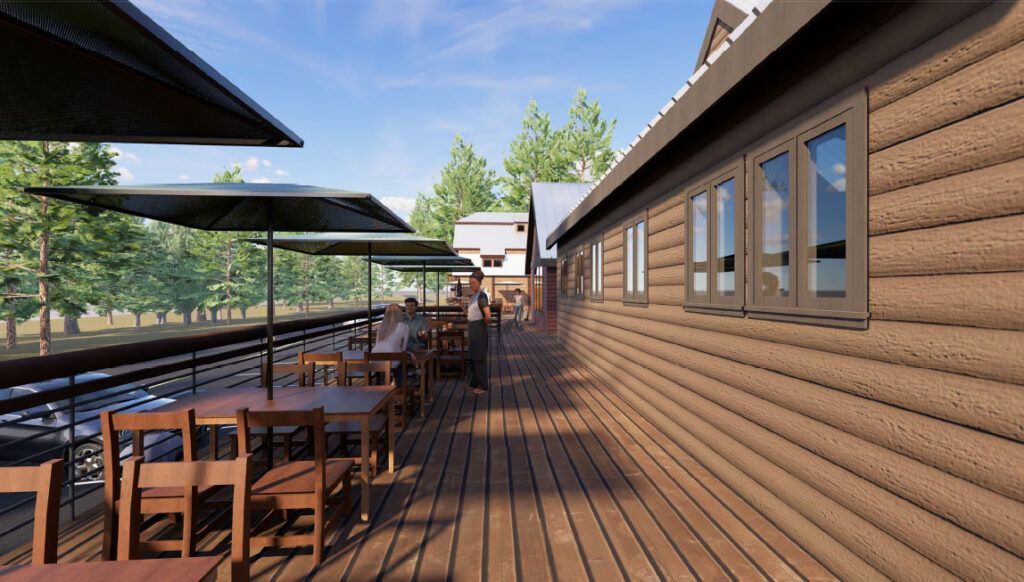Outdoor cafe with wooden tables, umbrellas, and a wood-paneled building; trees and a train track are in the background.