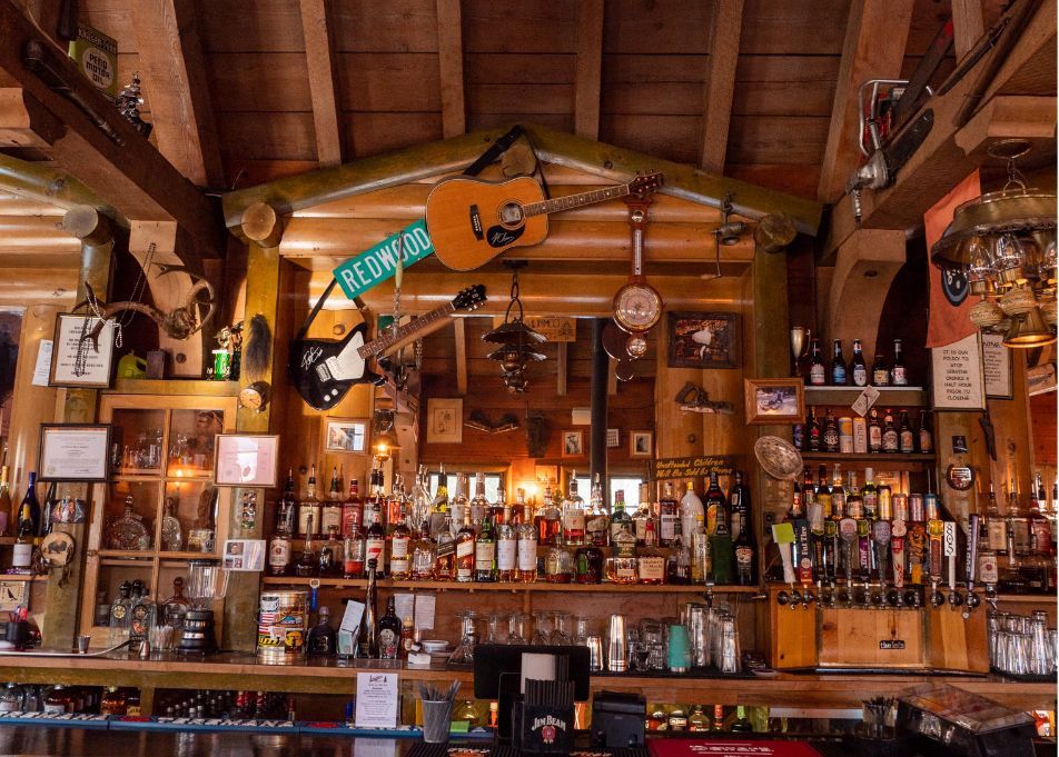 Bar interior with wooden ceiling, a fully stocked bar, and musical instruments hanging.