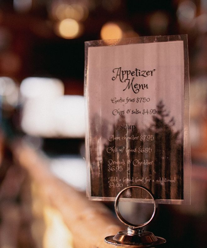 Appetizer menu in a clear plastic holder on a wooden railing.