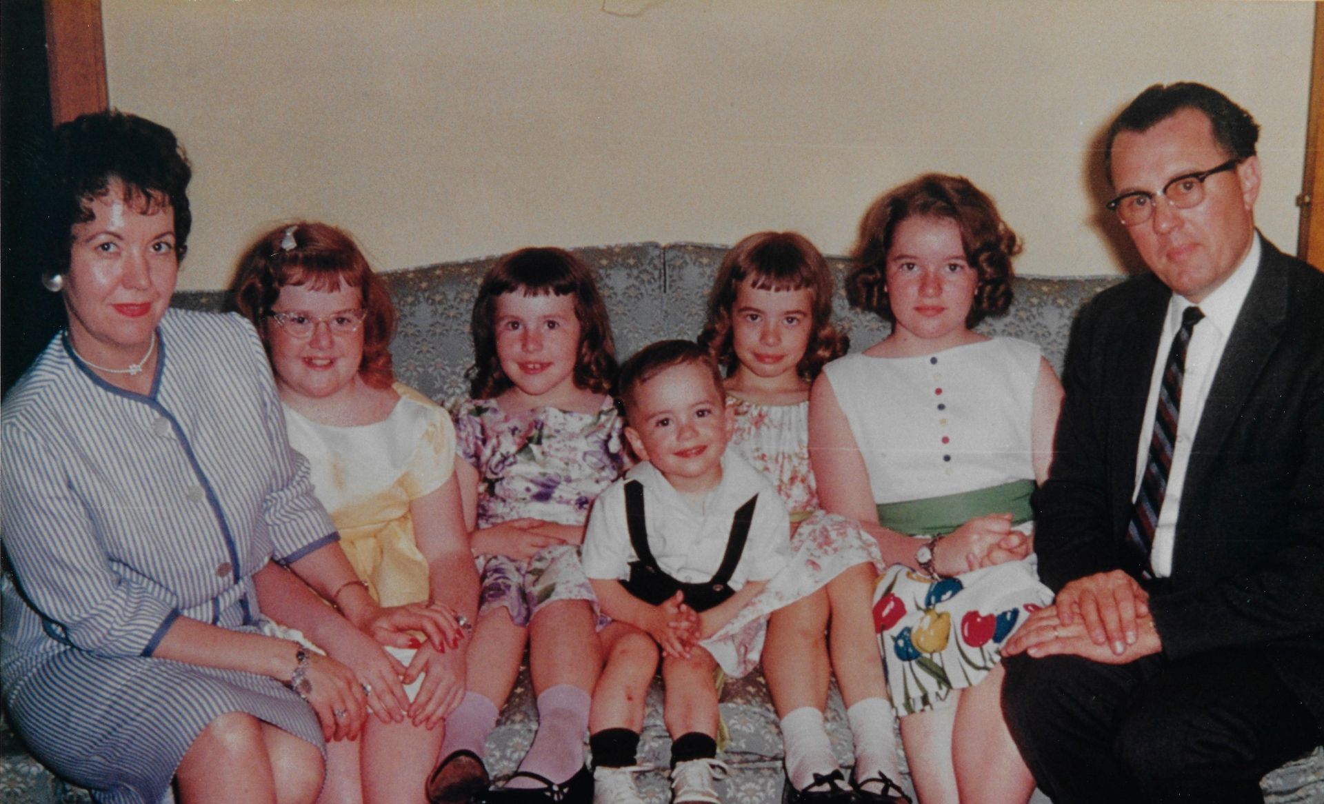 Family group seated on a couch, posing for a formal indoor portrait.