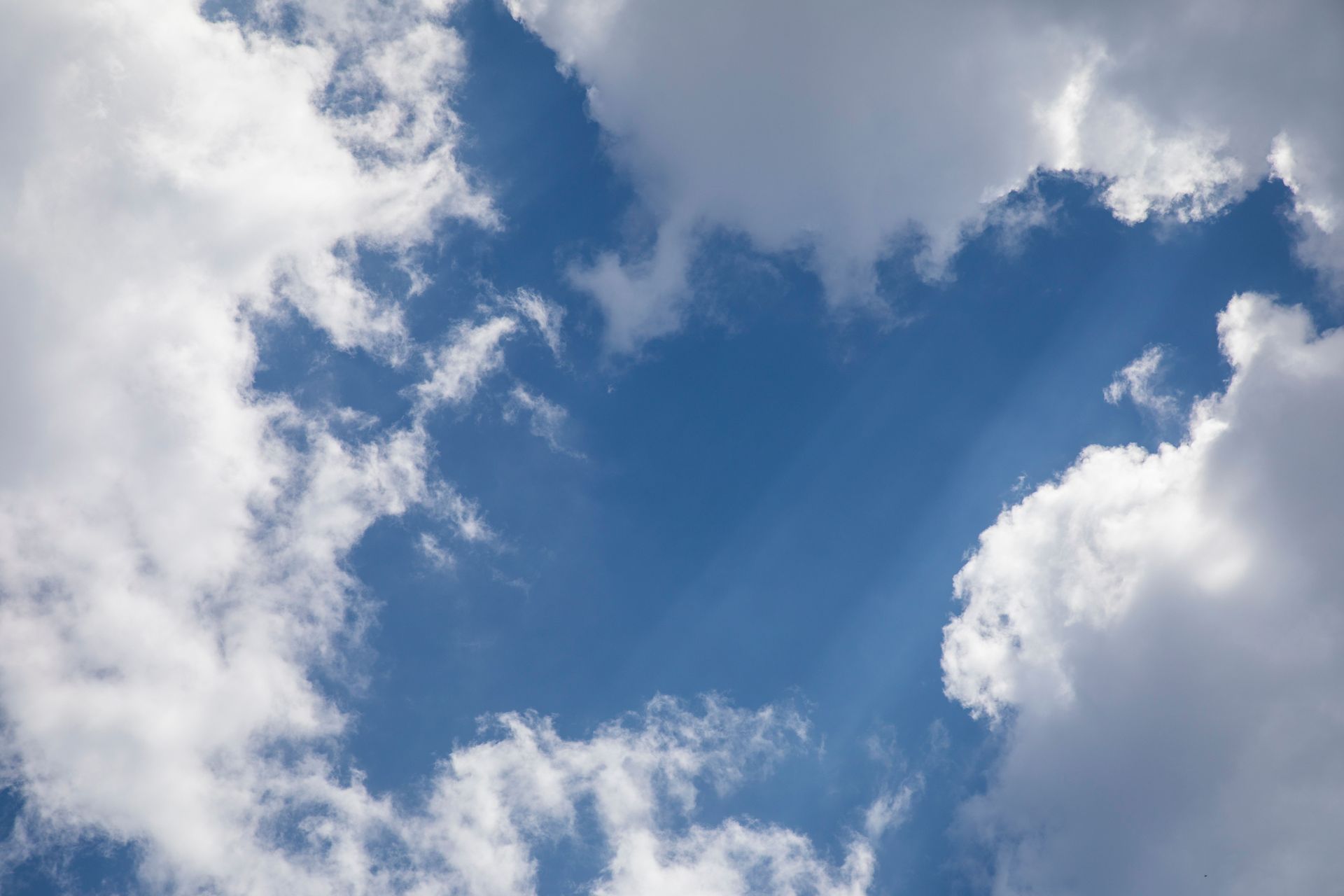 Blue sky with white clouds and sun rays breaking through the cloud cover