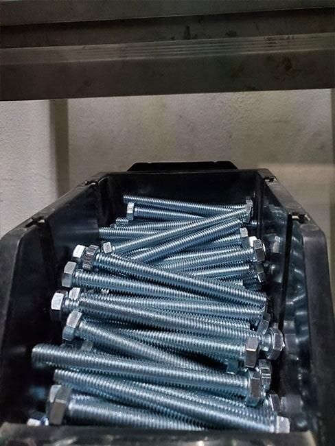 Un montón de tornillos están apilados uno encima del otro en un contenedor.