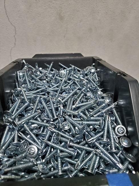 Un montón de tornillos en un contenedor negro sobre una mesa.