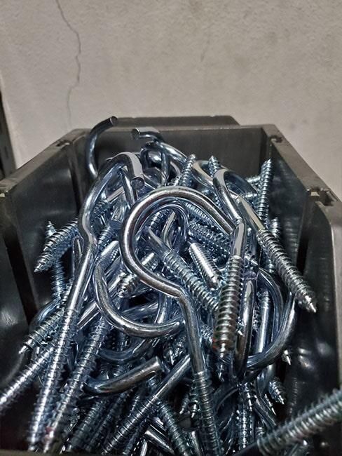 Un montón de tornillos y ganchos en un recipiente de plástico.