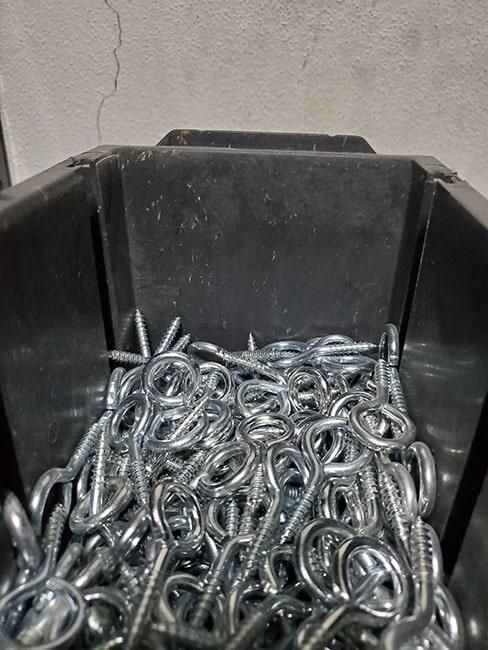 Un contenedor negro lleno de muchos tornillos y cadenas.