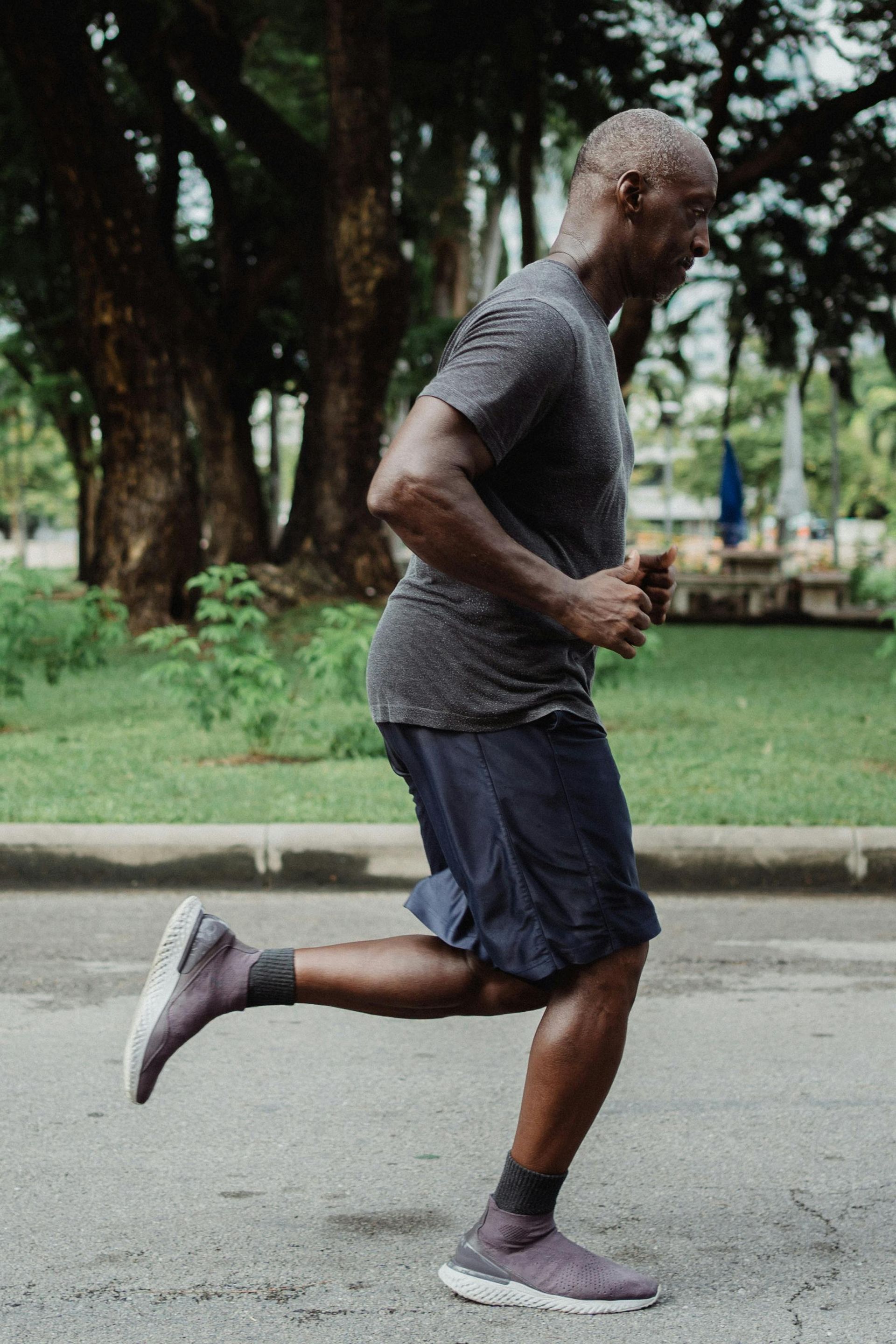 A man is running down a street in a park.