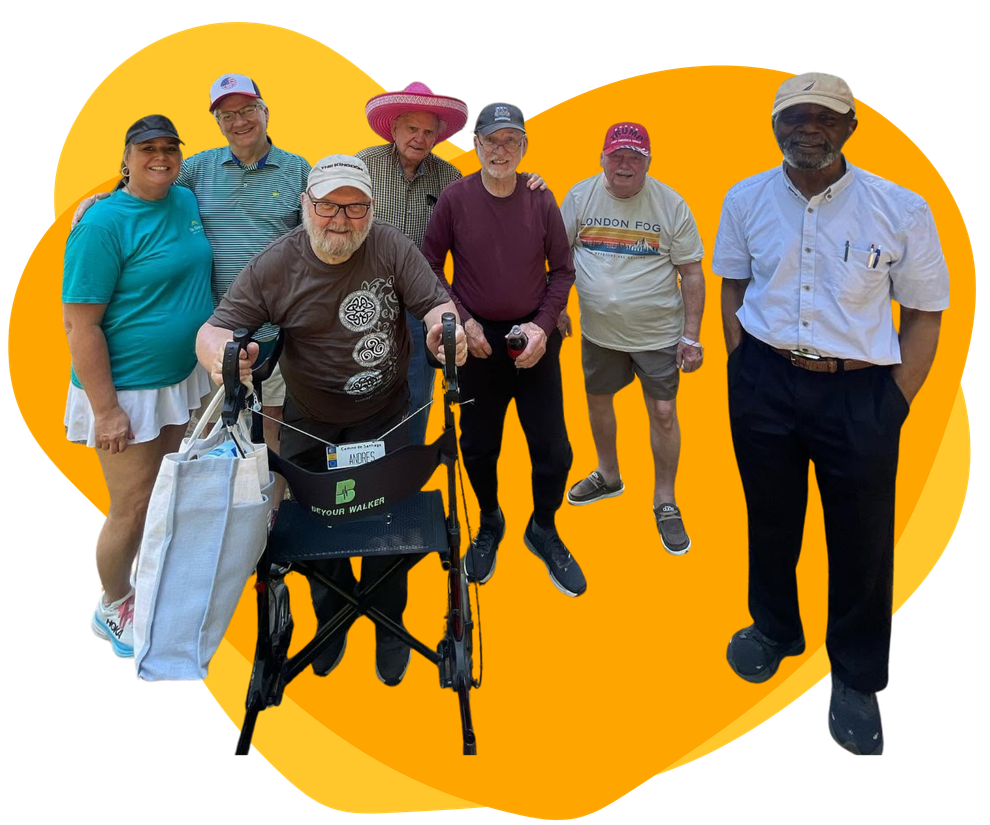 Group of seven people standing together, one using a walker, on a bright orange background