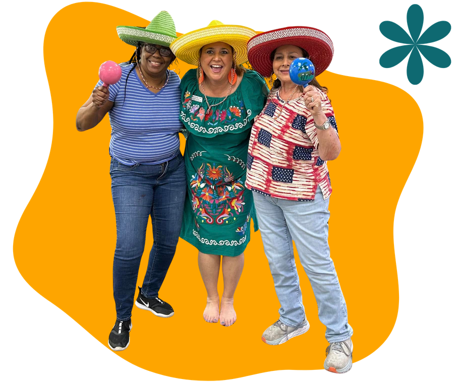 Three people in colorful sombreros smiling and posing against an orange background