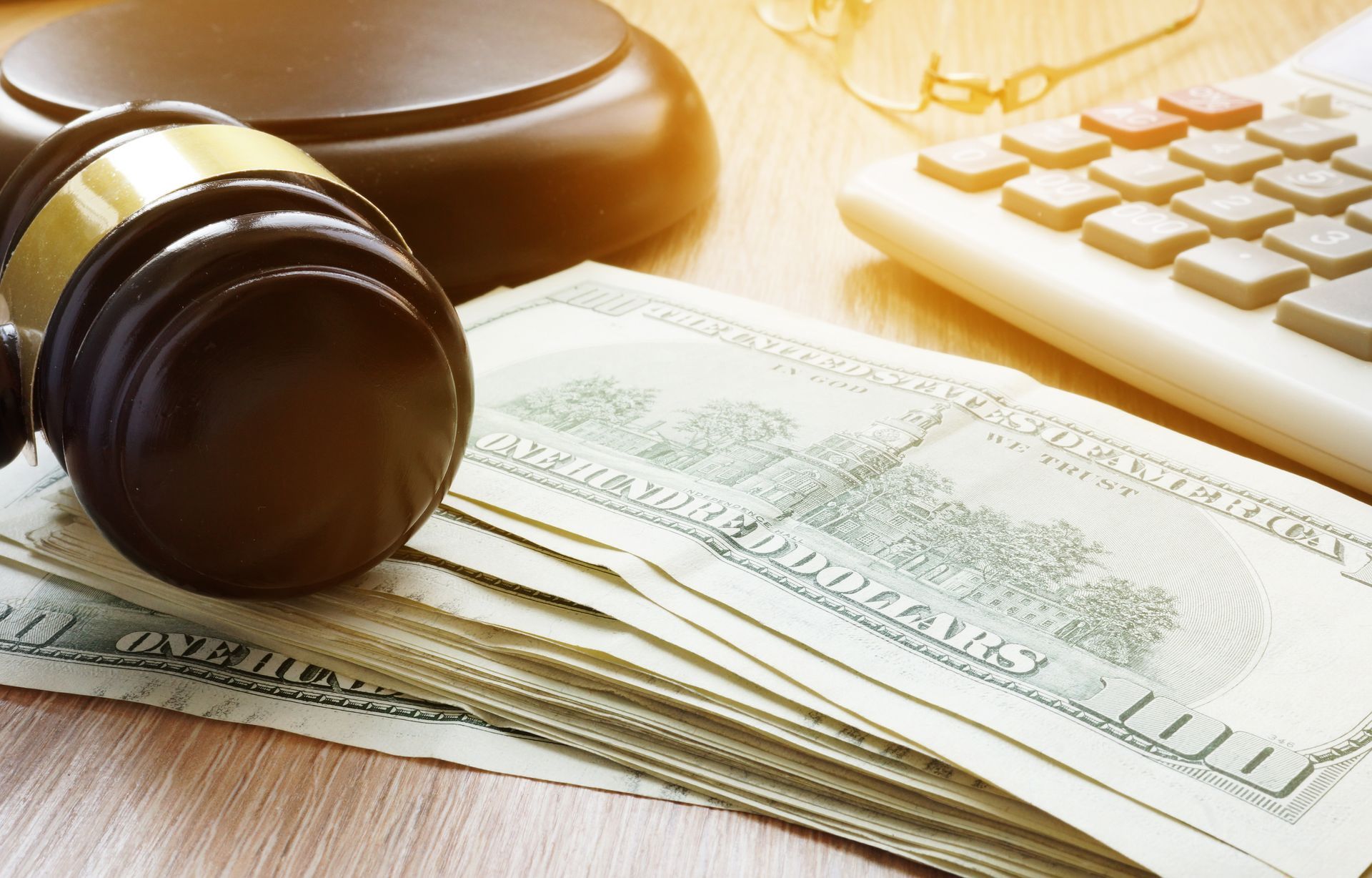 Judge’s gavel on stacks of dollar bills beside a keyboard, suggesting legal and financial matters