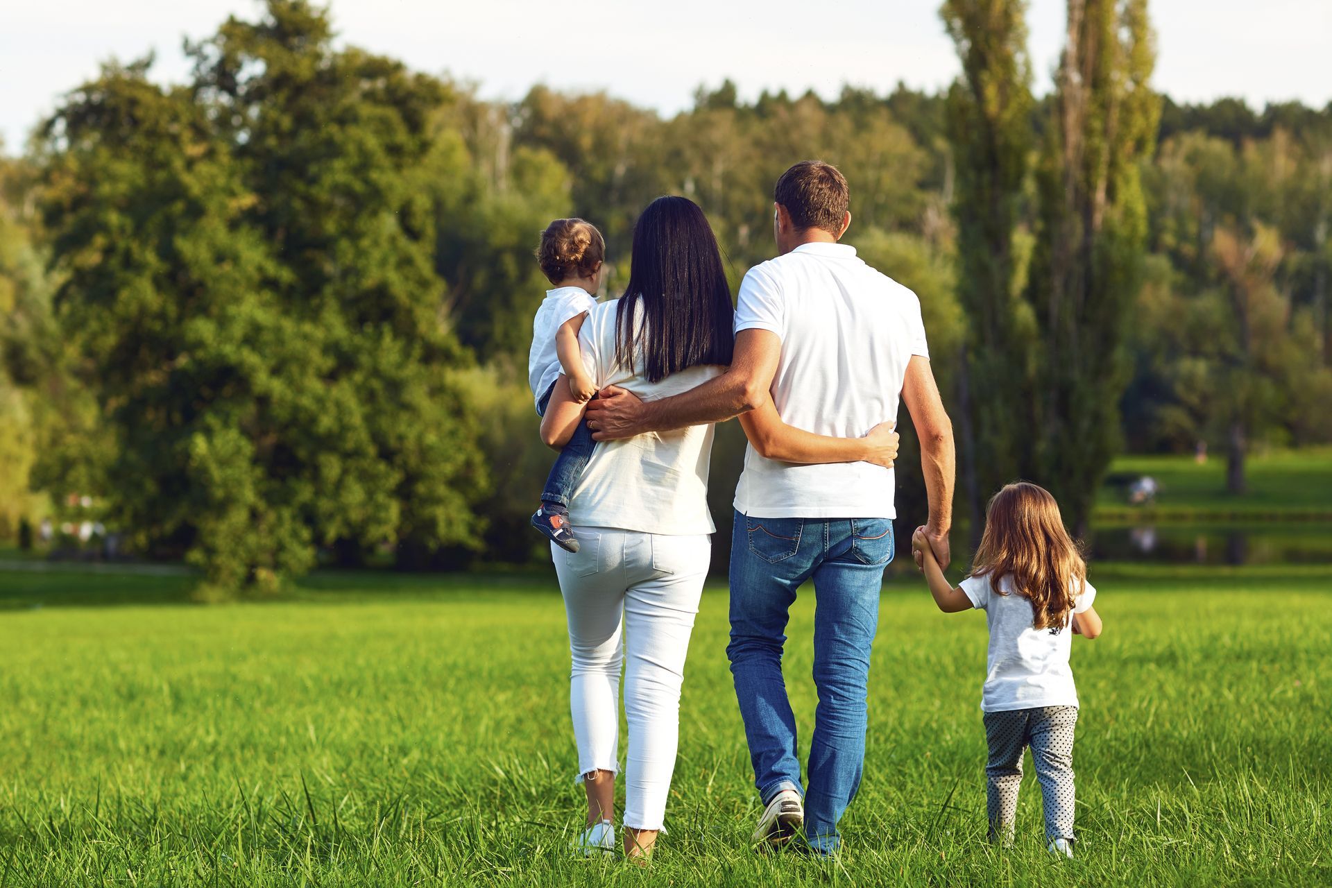Family walking hand in hand through a green park on a sunny day
