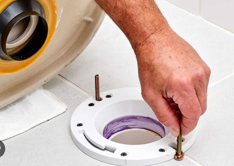 A person is fixing a toilet with a screwdriver