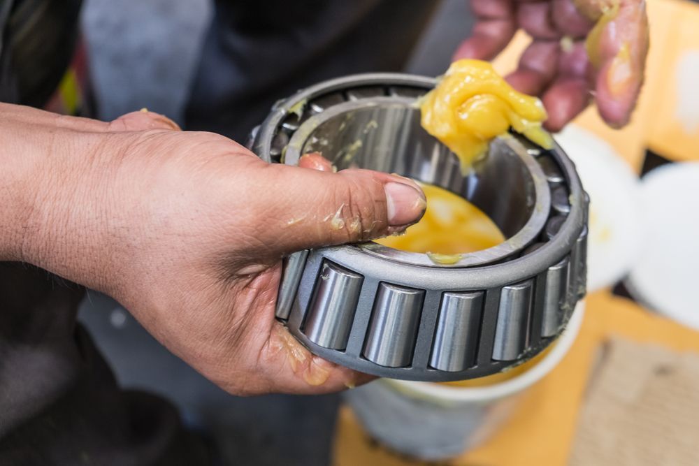 A Person Applies Yellow Lubricant Grease — Eastcoast Bearings & Hydraulics in Woolgoolga, NSW