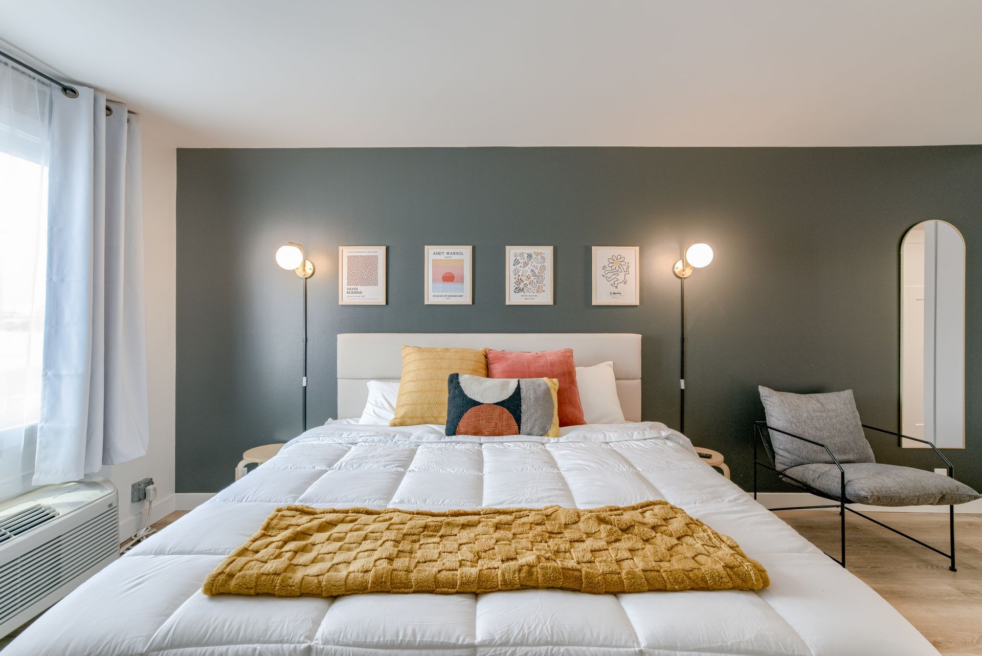 A bedroom with a large bed , chair , and mirror.