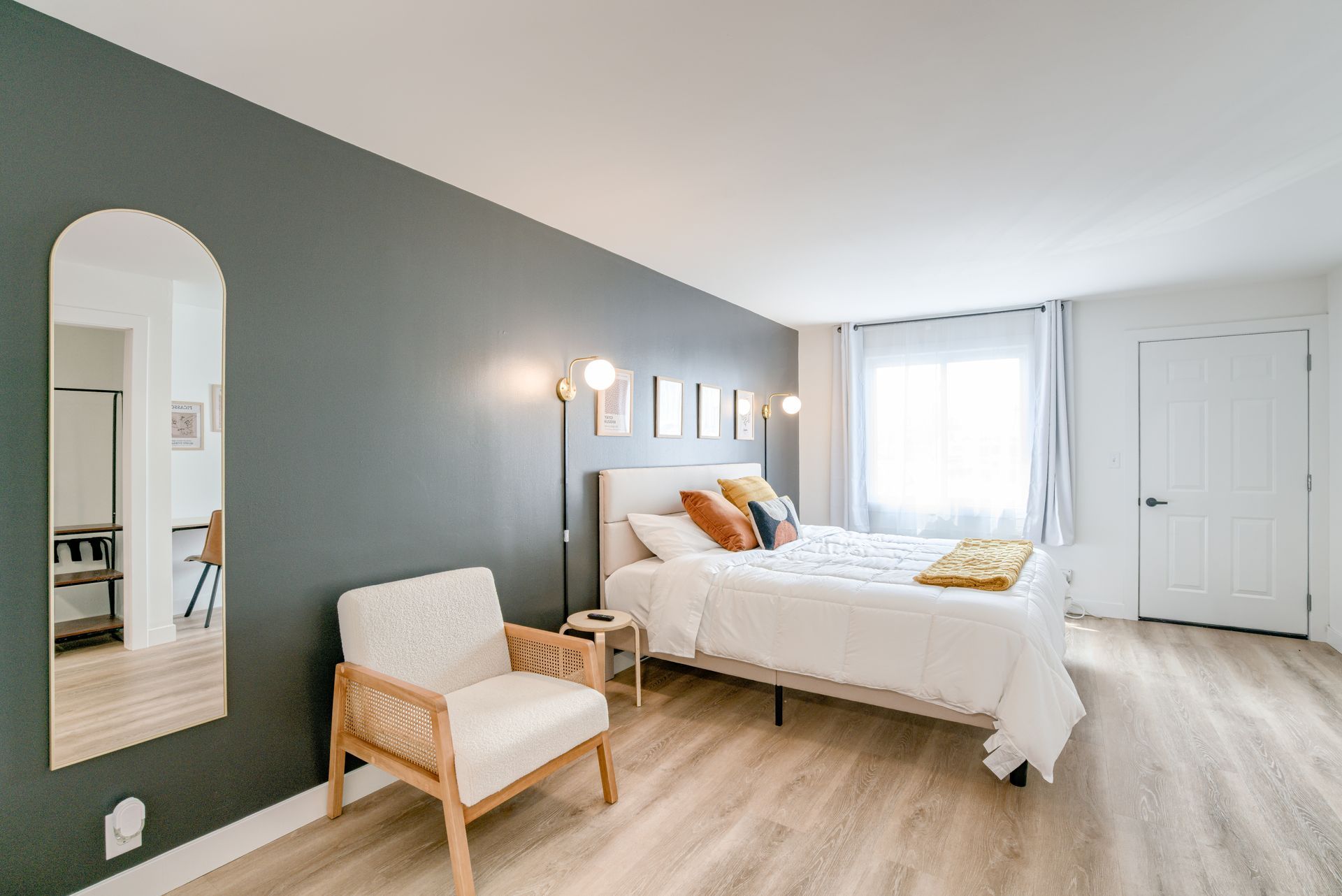 A bedroom with a large bed , chair and mirror.