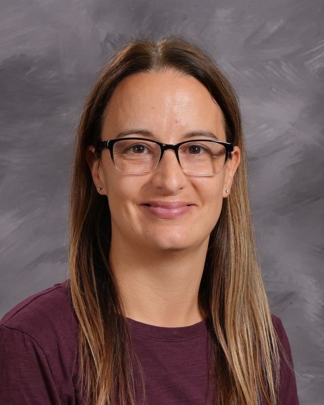 A woman with long hair wearing glasses and pink shirt smiling for the camera