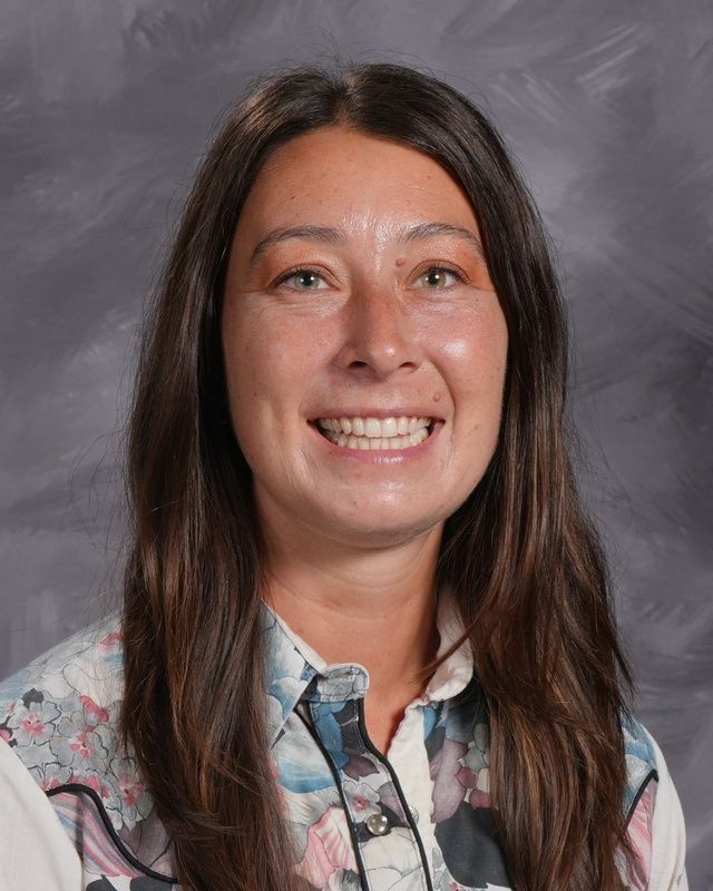 A woman wearing a printed shirt smiles for the camera