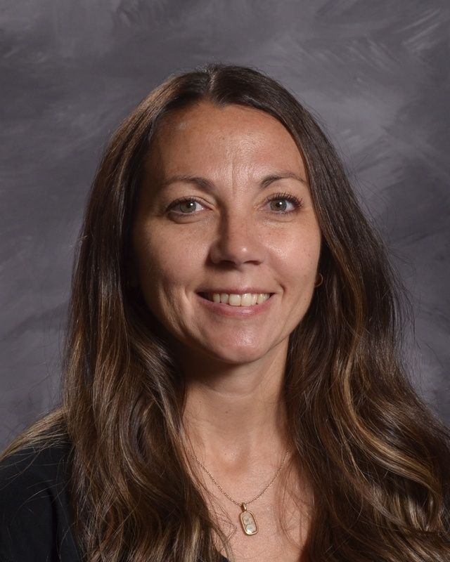 A woman with long brown hair is smiling for the camera